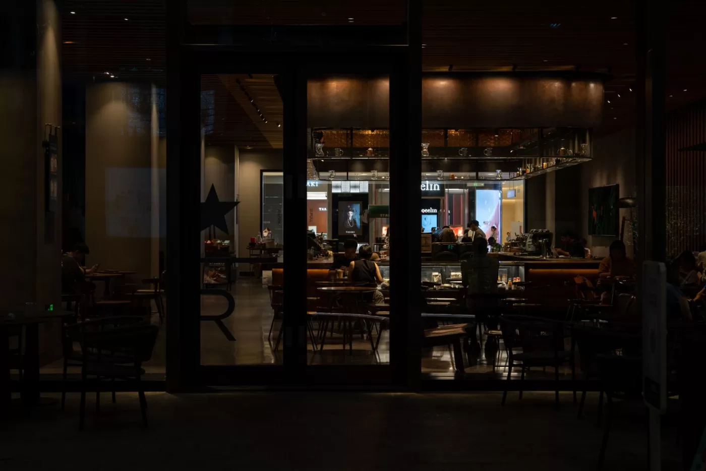Warm and inviting nighttime interior view of a modern cafe with patrons enjoying the ambiance.