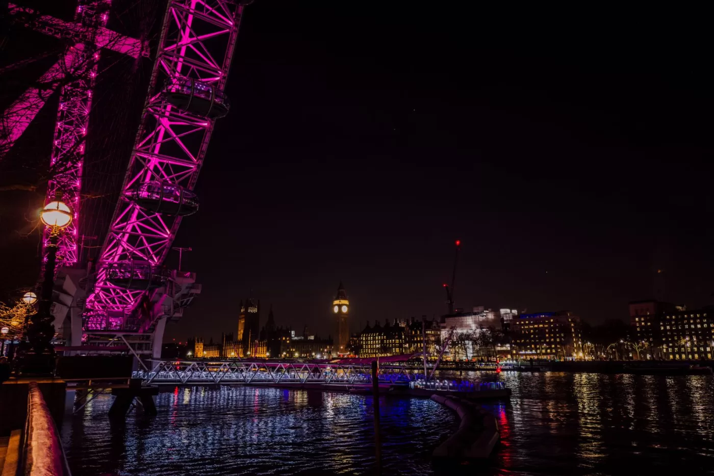 Dazzling night view of London's landmarks including the London Eye and Big Ben reflecting on the Thames.