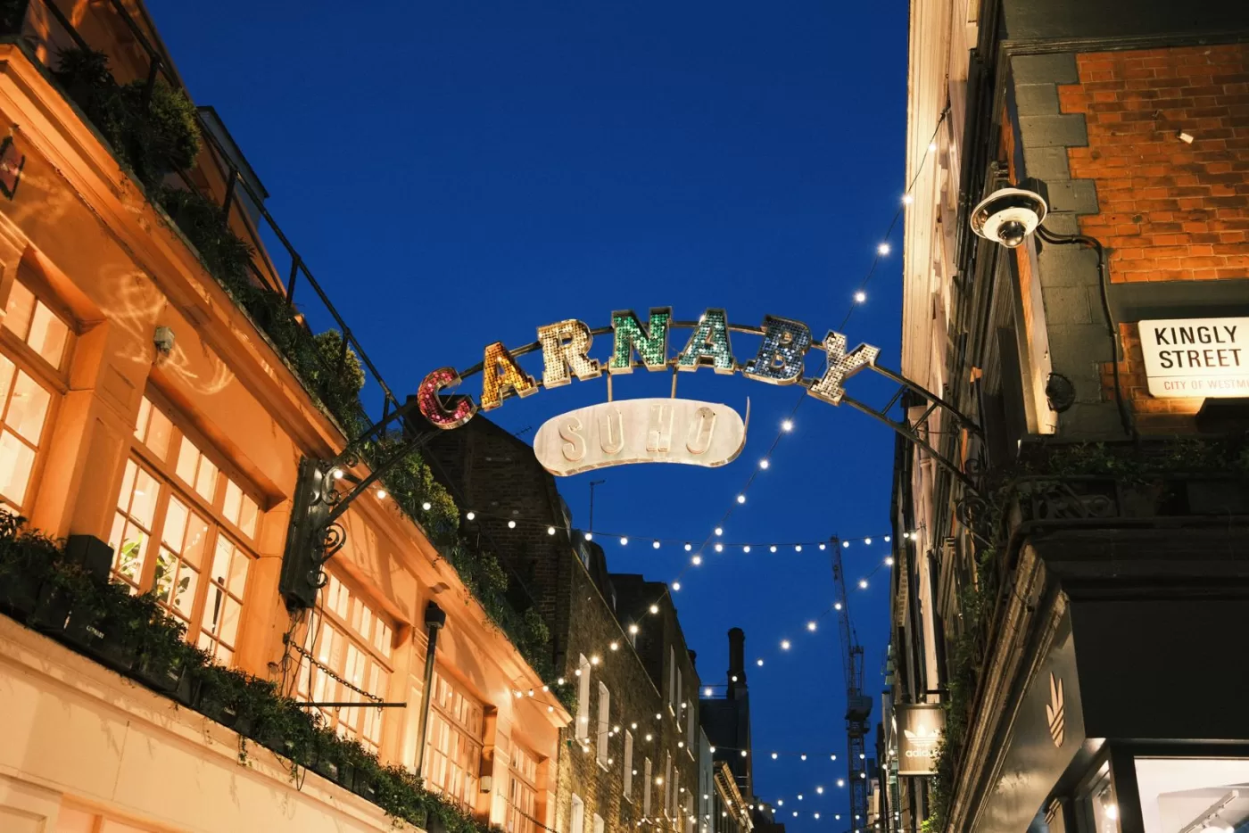 Illuminated Carnaby Street sign in Soho, London, showcasing vibrant nightlife atmosphere.