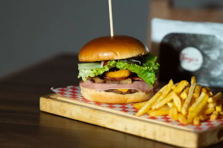 Delicious burger with fries on wooden platter