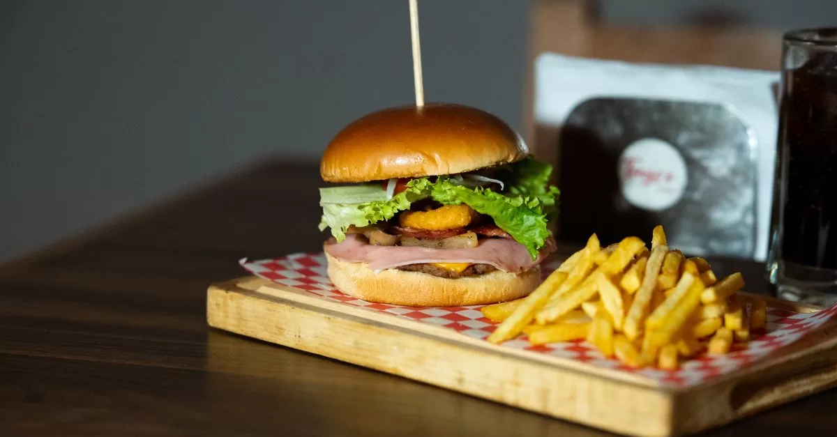 Delicious burger with fries on wooden platter