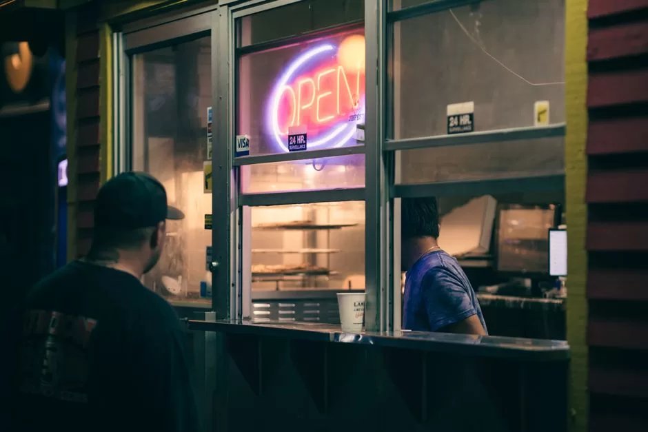A late night food counter lit by a neon open sign