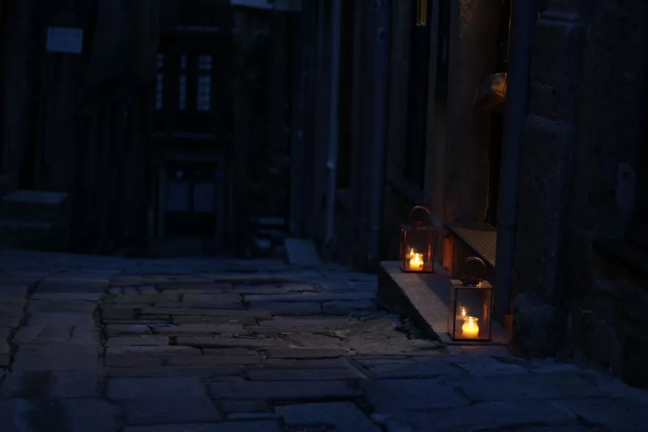 A dark stone passage lit by candles