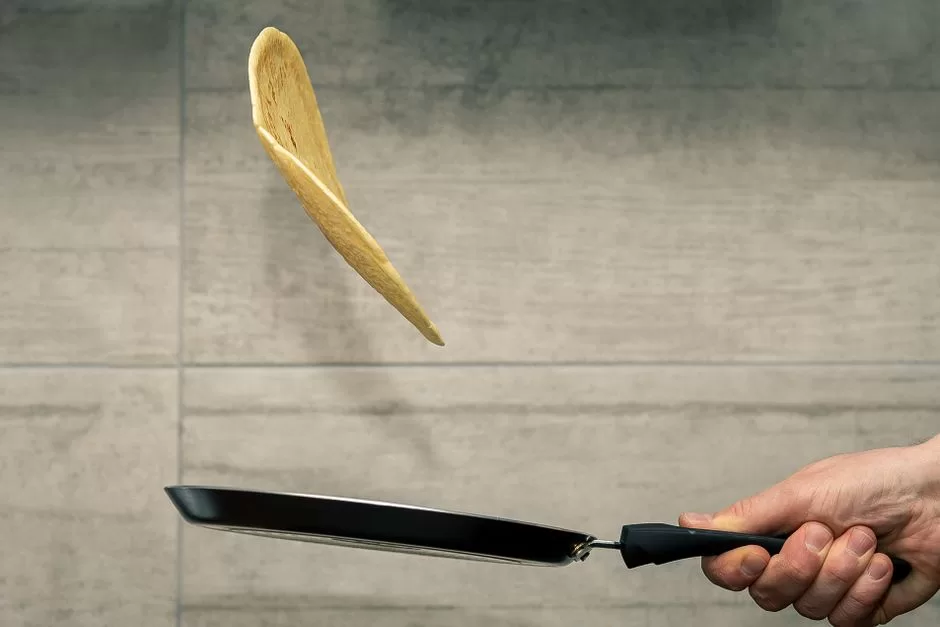 A pancake being flipped in a pan
