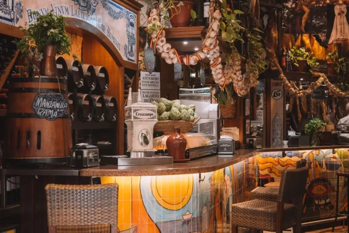 A bar counter with plants, barrels and patterned tiles