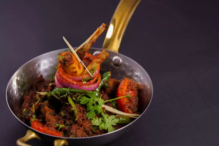 Spicy lamb curry in traditional indian brass pot