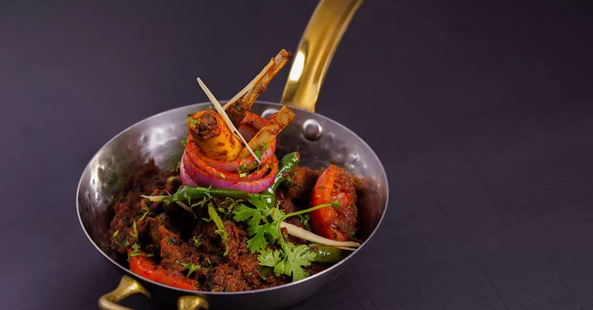 Spicy lamb curry in traditional indian brass pot
